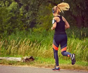 A woman is running with the pedometer on her arm.